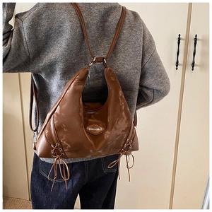 Detail of brown leather backpack featuring a round brand logo and side bow decorations