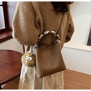 Detail of dark brown litchi leather bucket bag with silk scarf handle and plush charm