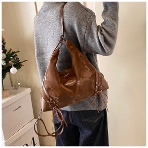 Close-up of vintage brown gloss tote bag with side lace-up detail and metal logo