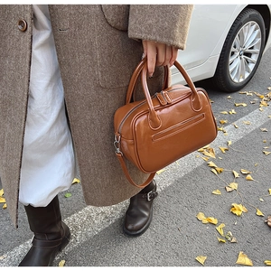 Outdoor shot of a caramel brown leather handbag on a street covered in ginkgo leaves