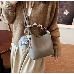 Close-up of gray pebble leather bucket bag with silk scarf handle and plush eye charm