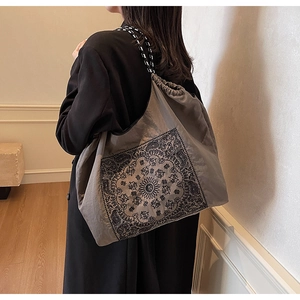 Close-up of gray drawstring tote bag with bohemian floral print and woven rope handle