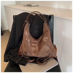 Detail of a vintage brown tote bag with decorative side lacing and metallic brand plate
