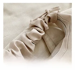 Detail of cream corduroy tote bag featuring a soft pleated cloud handle and zipper closure