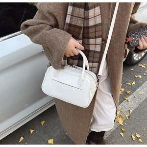 Close-up of white glossy PU leather handbag with dual handles and adjustable shoulder strap