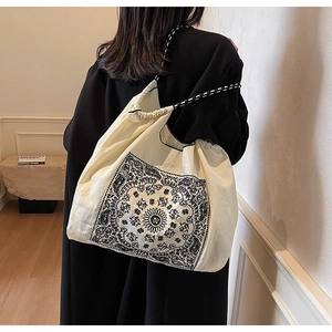 Model view of ivory paisley tote bag with woven drawstring straps and boho pattern