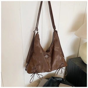 Detail of dark brown leather hobo bag with silver eyelets and drawstring accents