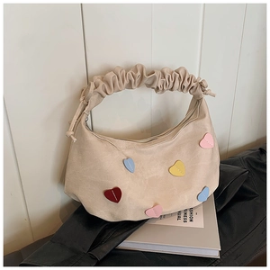 Detail of cream canvas bag featuring colorful heart patches and ruffled drawstring handle