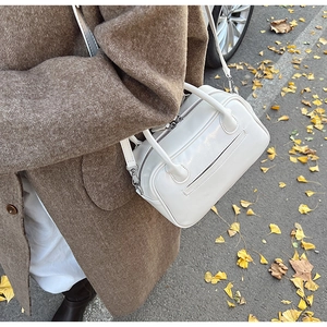 Close-up of a white leather Boston handbag featuring dual handles and a detachable strap