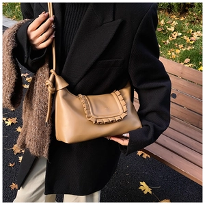 Detail of khaki leather shoulder bag featuring ruffled flap edge and tied strap details