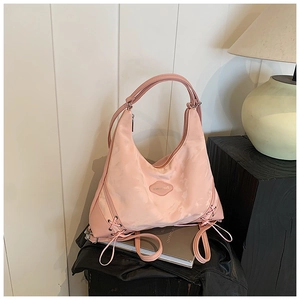 Detail of pink hobo tote bag featuring decorative side drawstrings and a zip closure