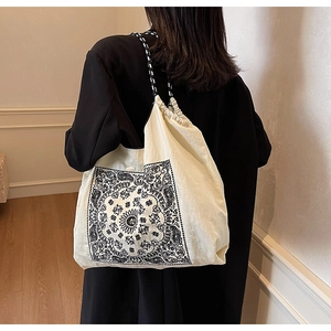 Rear view of model wearing a beige paisley canvas tote bag with woven rope handles