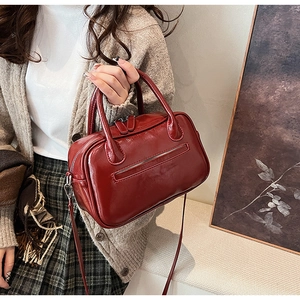 Deep red glossy patent leather Boston bag with reinforced handles and crossbody strap
