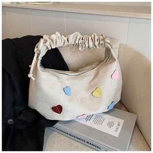 Detail of beige hobo bag with pleated cloud handle and colorful heart-shaped patches