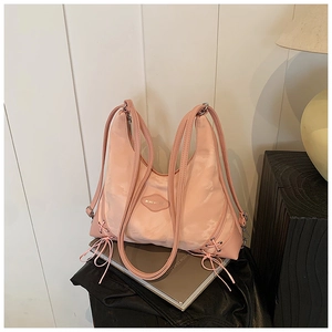 Detail of pink tote bag showing glossy nylon texture with side bow ties and metal logo