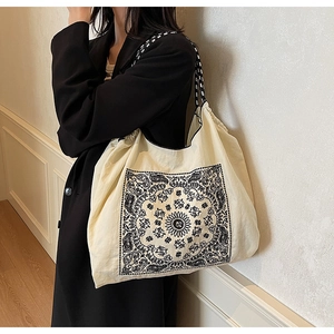 Detail of vintage paisley pattern on beige canvas tote bag with woven shoulder straps
