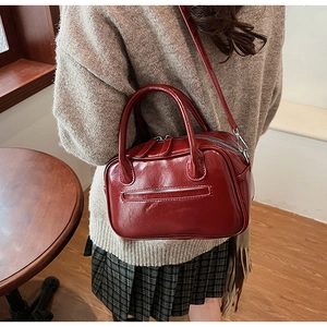 Chic dark red glossy patent leather bowling bag shown in a vintage interior setting