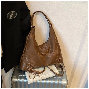 Detail of vintage brown tote bag featuring cross-lace side design and leather texture