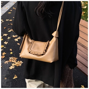 Detail of tan leather shoulder bag with ruffle edge and decorative side knots