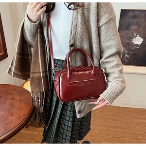 Detail of a vintage burgundy satchel with glossy finish and model styled in autumn attire