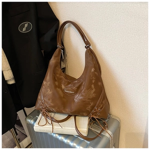 Macro view of vintage brown leather tote bag with side ribbon detail and silver logo tag