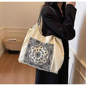 Detailed shot of ethnic tote bag featuring black paisley patterns and braided rope strap
