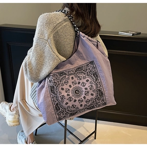 Detailed side view of purple drawstring tote bag with ethnic mandala print and woven strap