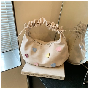 Macro shot of beige ruched handbag with colorful heart patches on a warm background