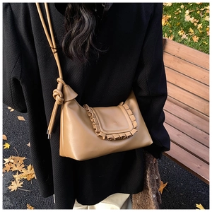 Close-up of vintage brown leather bag with ruffled edge and knotted strap detail