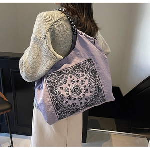 Detail of purple paisley drawstring tote bag with checkerboard strap in a lifestyle setting