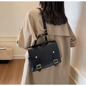 Detail of a vintage black leather backpack on a model wearing a beige trench coat
