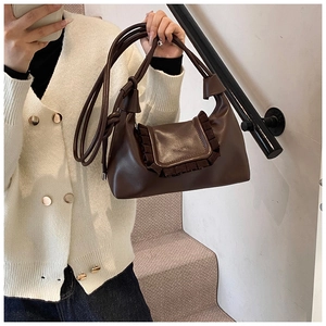 Detail view of a dark brown faux leather handbag with elegant pleated edge decoration