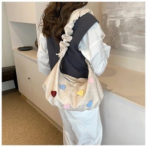 Detail of beige canvas bag with multi-color heart patches and ruched shoulder strap