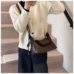 Detail of dark brown leather shoulder bag featuring vintage ruffle edge and knot strap