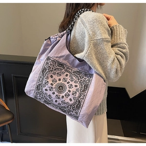 Macro shot of purple paisley tote bag with black and white geometric patterned strap