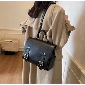 Detailed back view of vintage black leather satchel with gold buckles and adjustable strap