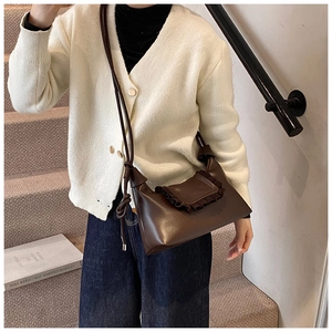 Detail of dark brown leather crossbody bag with ruffle trim and knotted strap detail