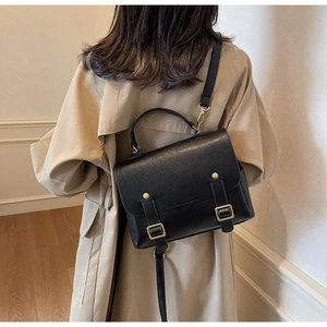 Detailed view of a vintage black faux leather satchel with gold buckles and straps