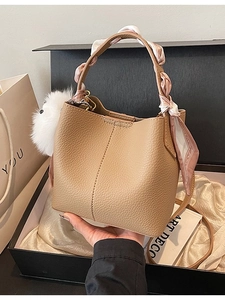 Minimalist beige pebble leather bucket bag with floral scarf and plush pompom charm