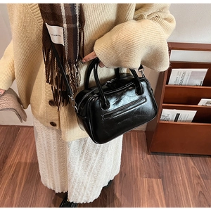 Detail of black glossy leather crossbody bag with wrinkled texture and vintage handles