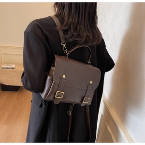 Detail of dark brown leather vintage backpack with buckle straps and top handle design