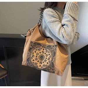 Detail of vintage brown tote bag featuring black ethnic mandala print and woven handles