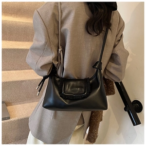 Detail of black pleated crossbody bag with silver accents on a tan blazer outfit