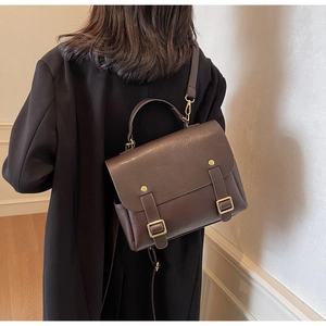 Detail of vintage dark brown leather messenger bag featuring metallic buckle straps