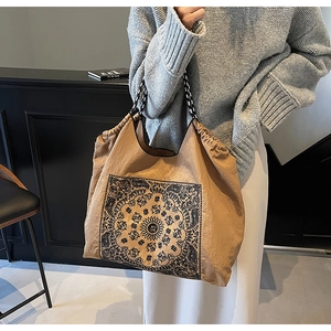 Detail of vintage tote bag featuring black mandala prints and woven geometric strap