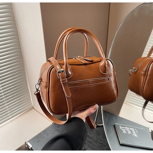 Detailed view of a brown faux leather Boston bag with dual handles and silver hardware