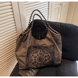 Detail of taupe tote bag with vintage mandala print and rope handles on a chair