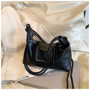 Detail of black leather shoulder bag with ruffled edges and knotted strap design