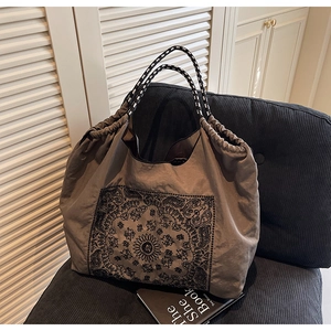 Close-up of vintage paisley print tote bag with woven rope handles and drawstring detail