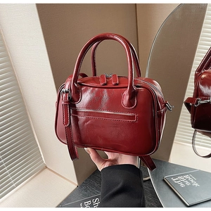 Detailed macro of the vintage burgundy pleated leather Boston bag with dual zippers